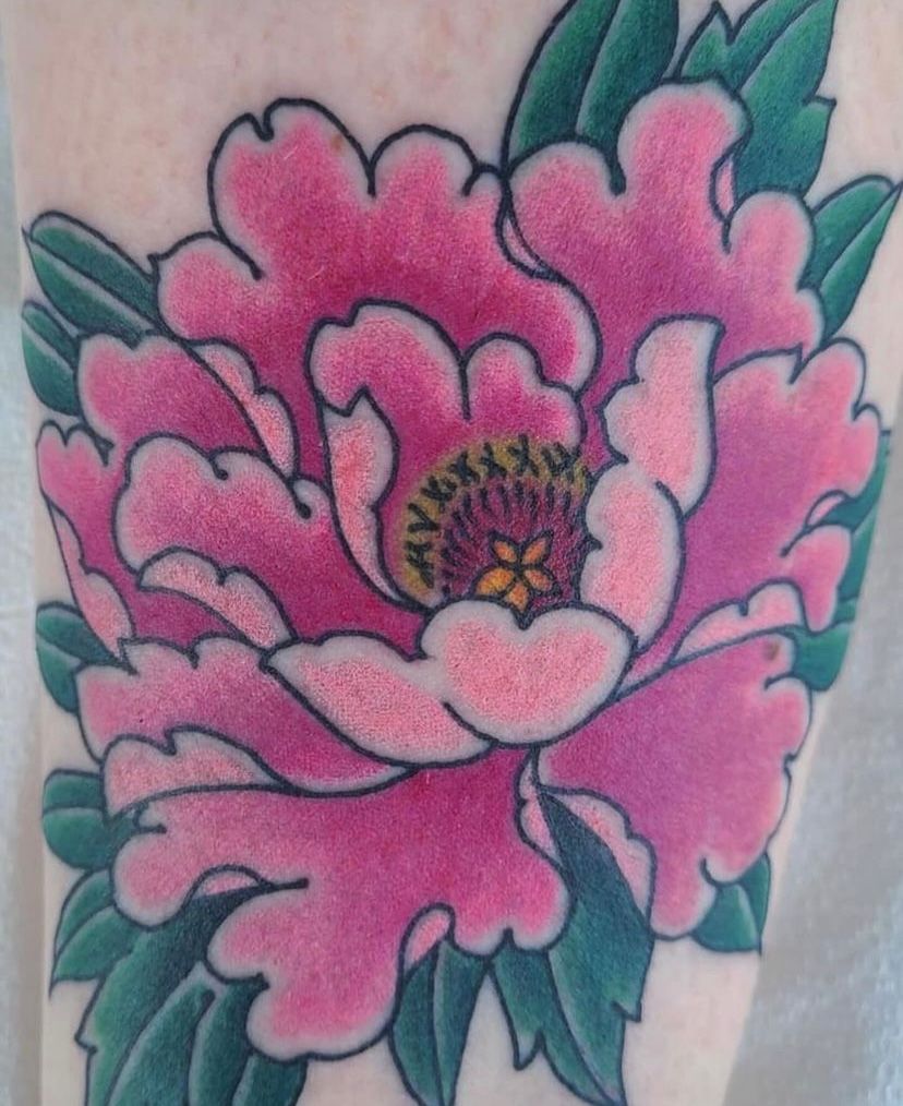 a tattoo of a pink flower with green leaves