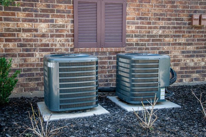 two air conditioners are sitting on the side of a brick building .