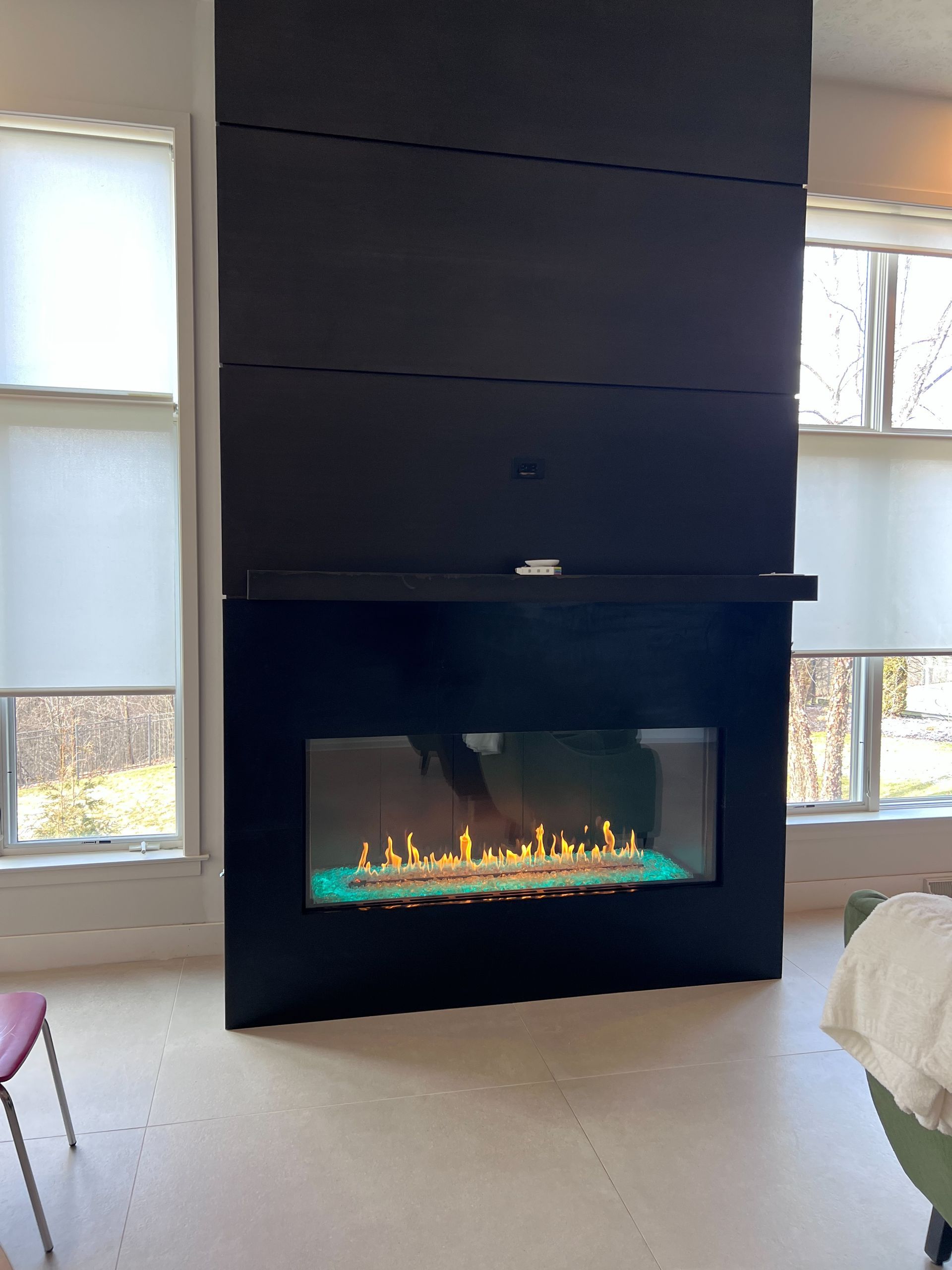 A fireplace is sitting in a living room next to a window.