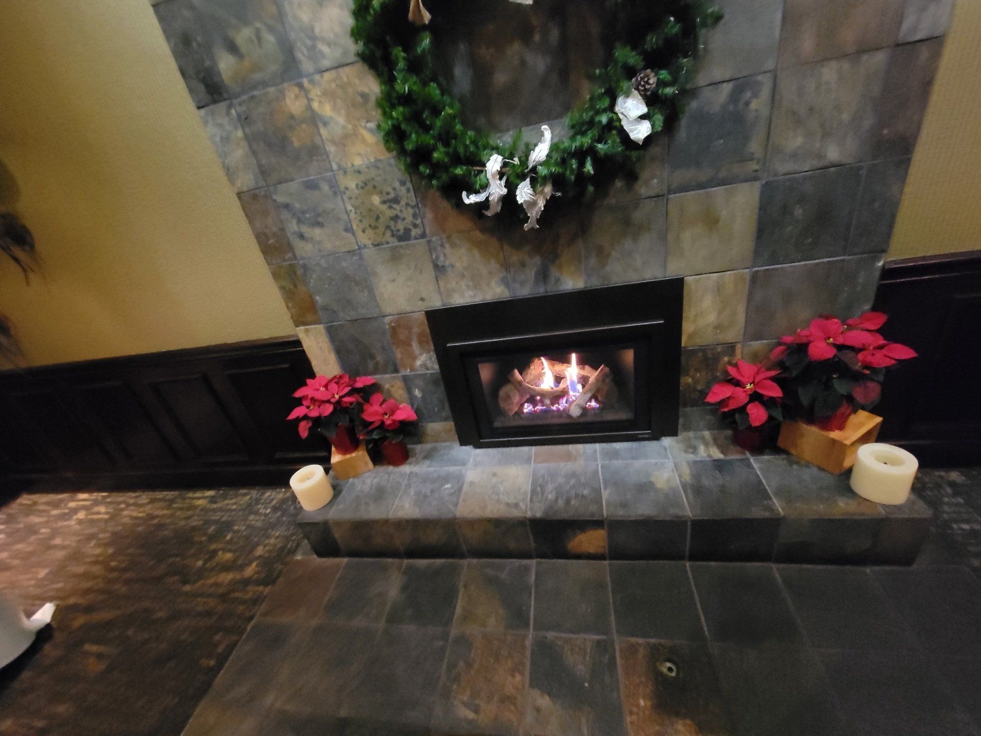 A fireplace with a wreath and candles on it