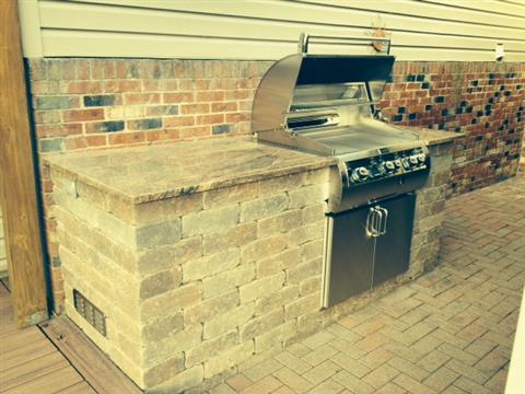 An outdoor grill is built into a brick wall.