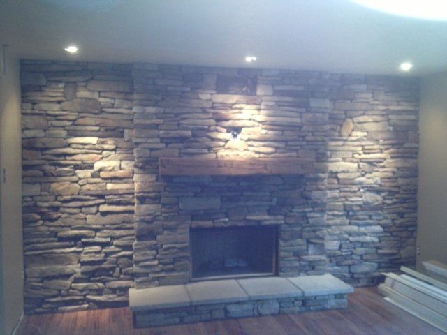 A living room with a fireplace and a stone wall