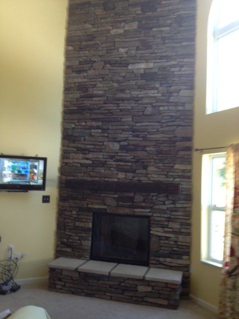 A living room with a large stone fireplace and a flat screen tv
