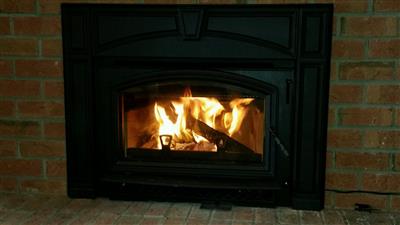 Fireplace with flames burning inside; set against a brick wall.