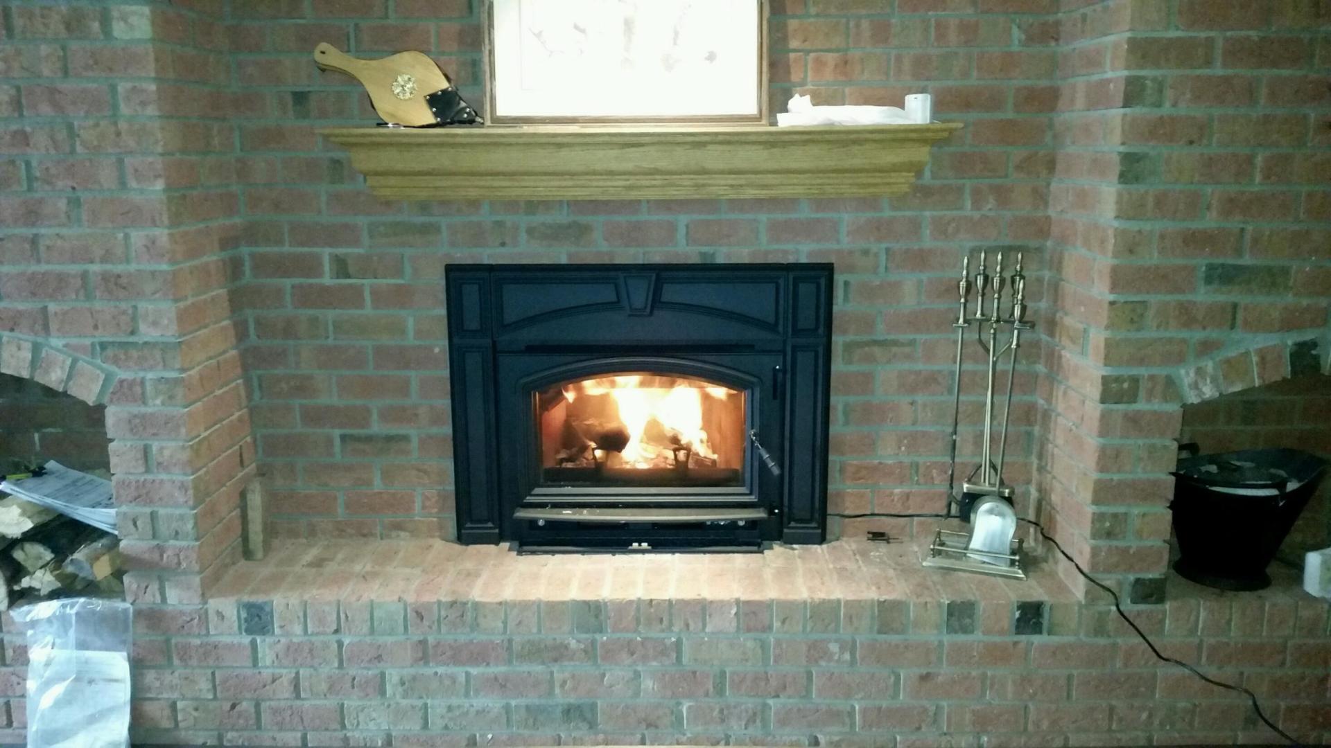 A brick fireplace with a wood stove in it
