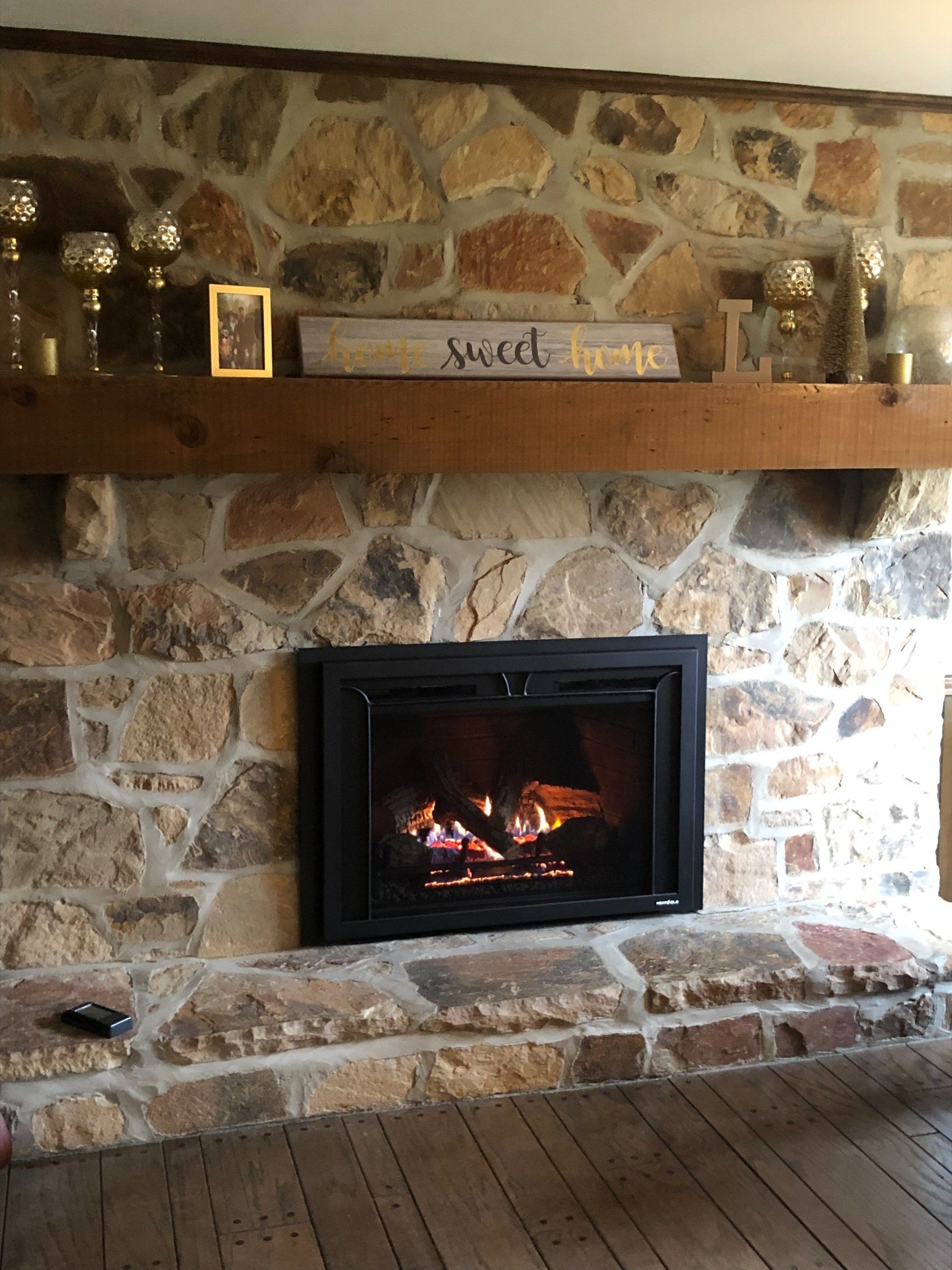 There is a fireplace in the middle of a stone wall.