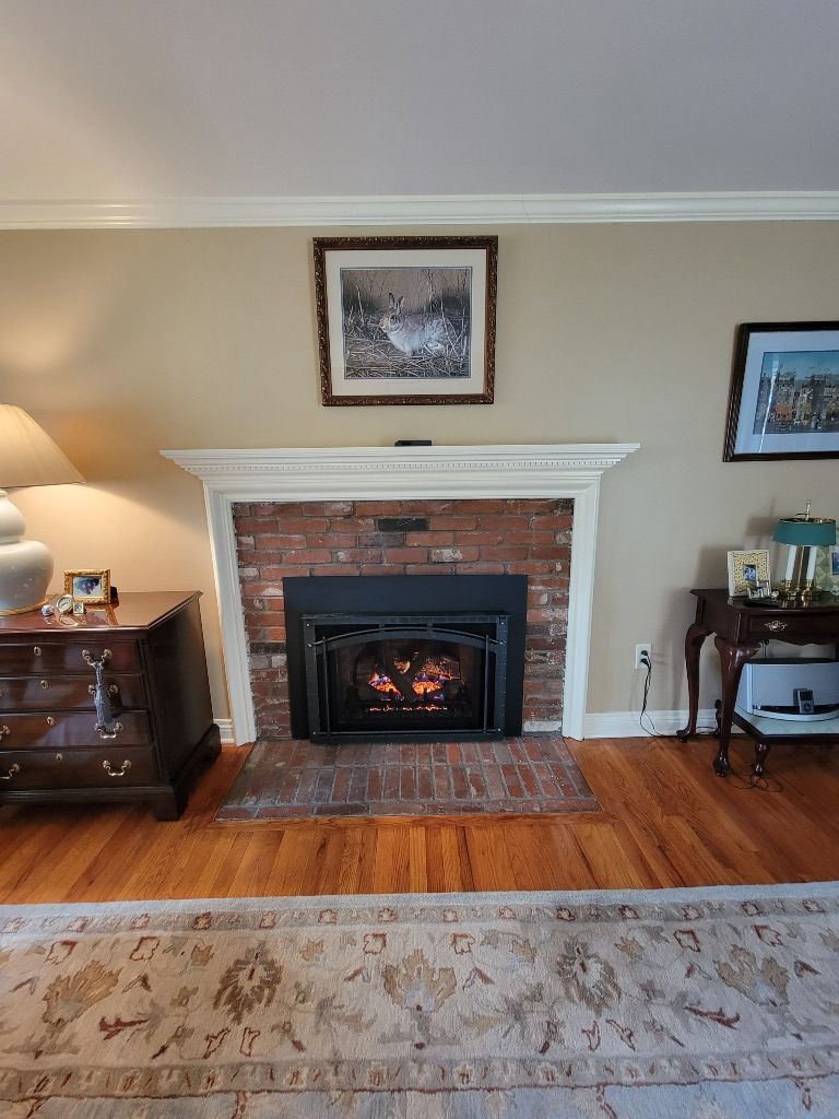 A living room with a fireplace and a picture on the wall.