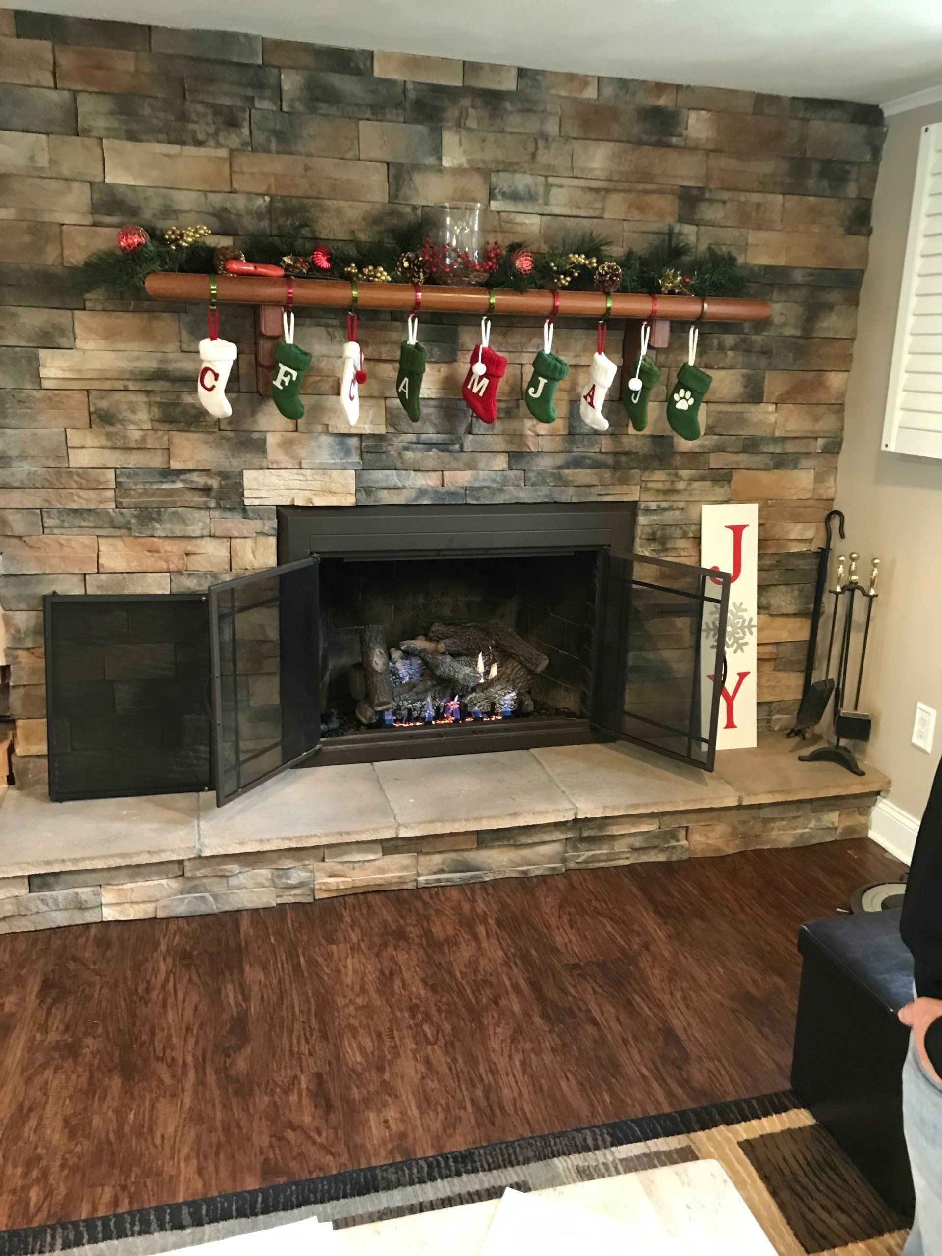 A living room with a fireplace decorated for christmas