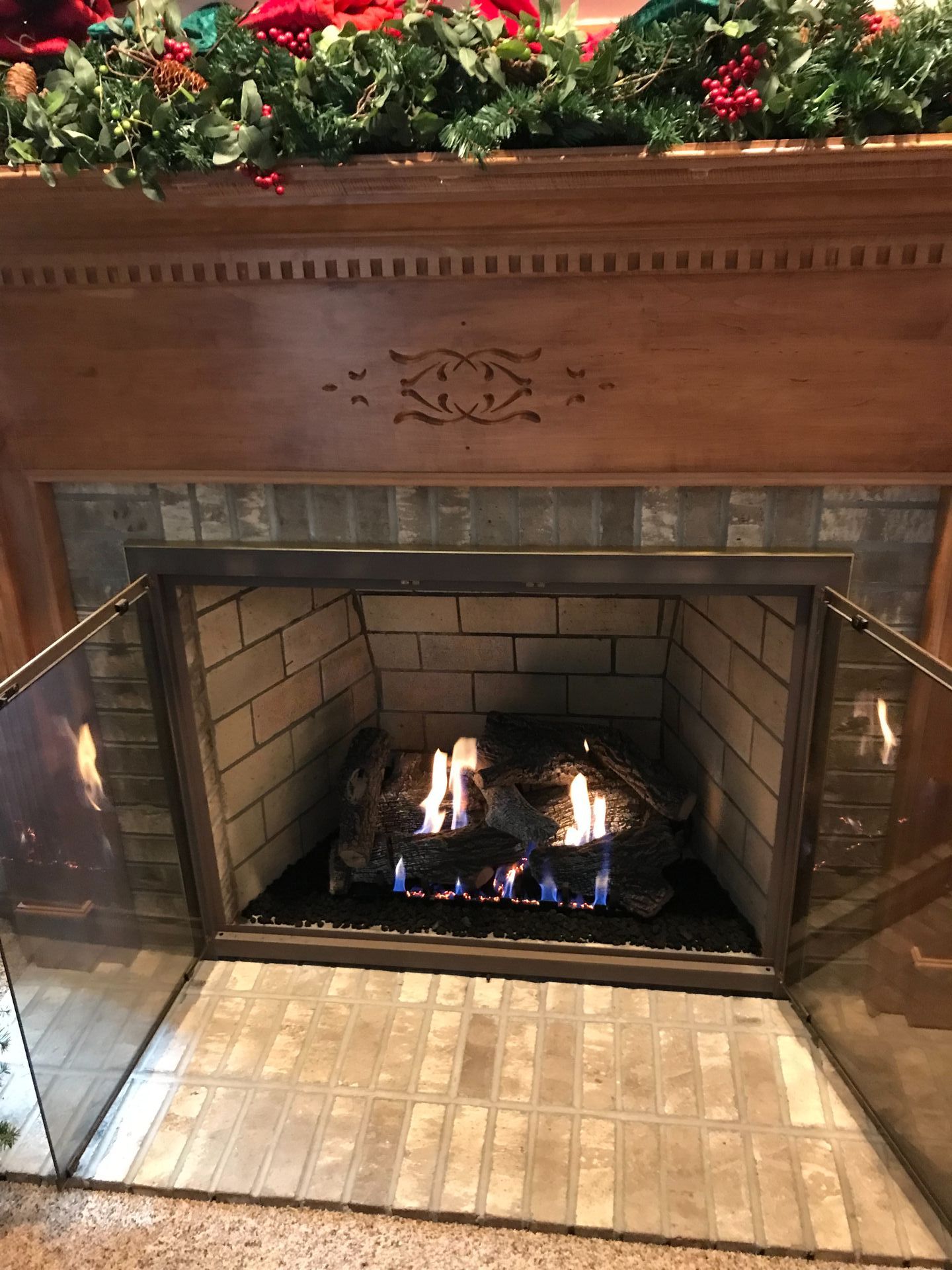 A fireplace with a glass door and a wooden mantle.