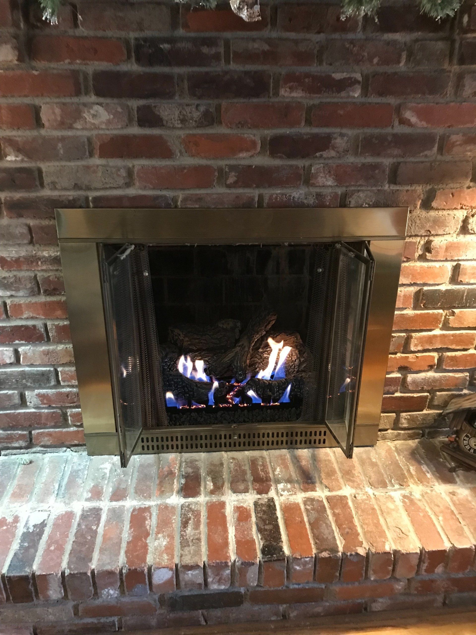 A brick fireplace with flames coming out of it.