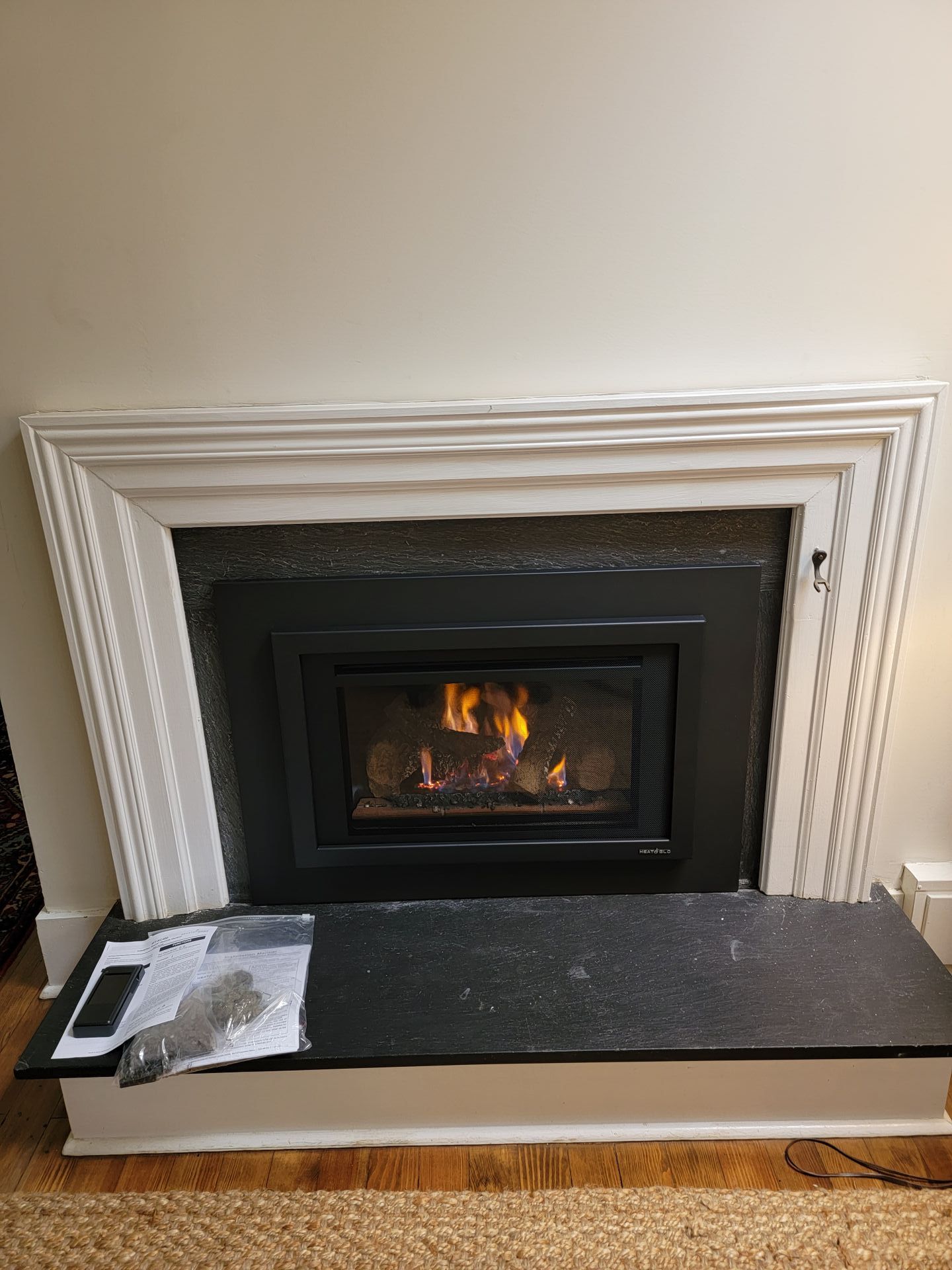 A living room with a fireplace and a black marble mantle.