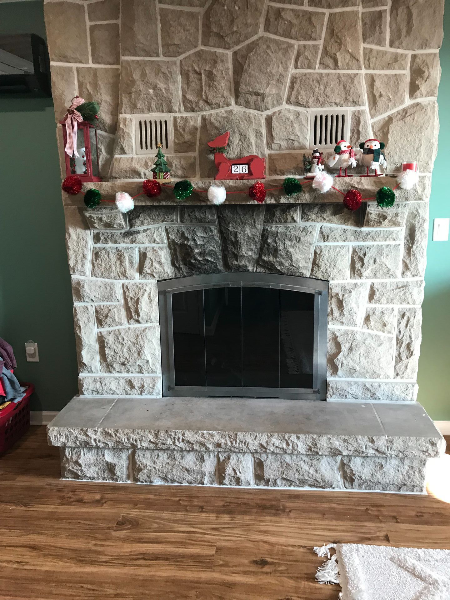 A stone fireplace with a mantle decorated for christmas.
