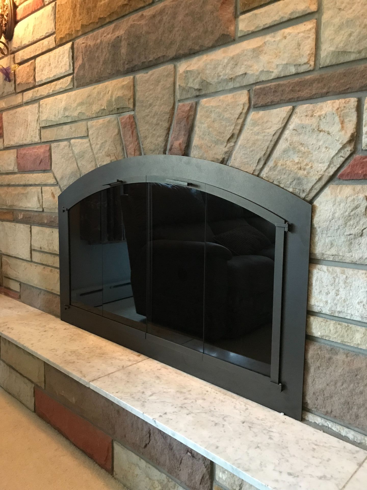 A fireplace with a glass door and a brick wall in a living room.