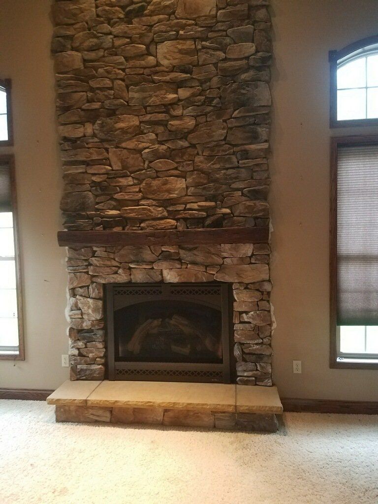 There is a large stone fireplace in the middle of the room.