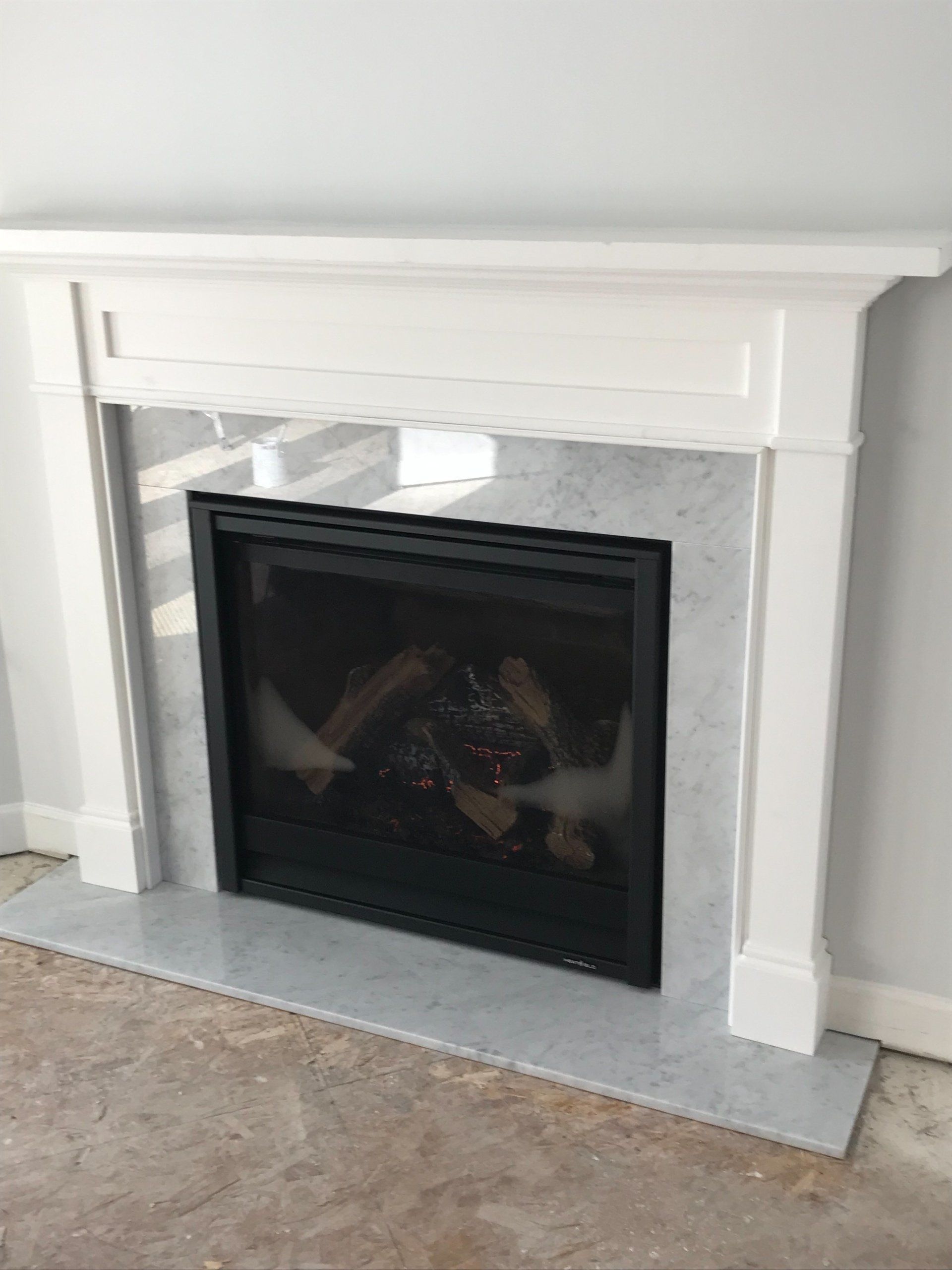A fireplace with a white mantle in a living room.