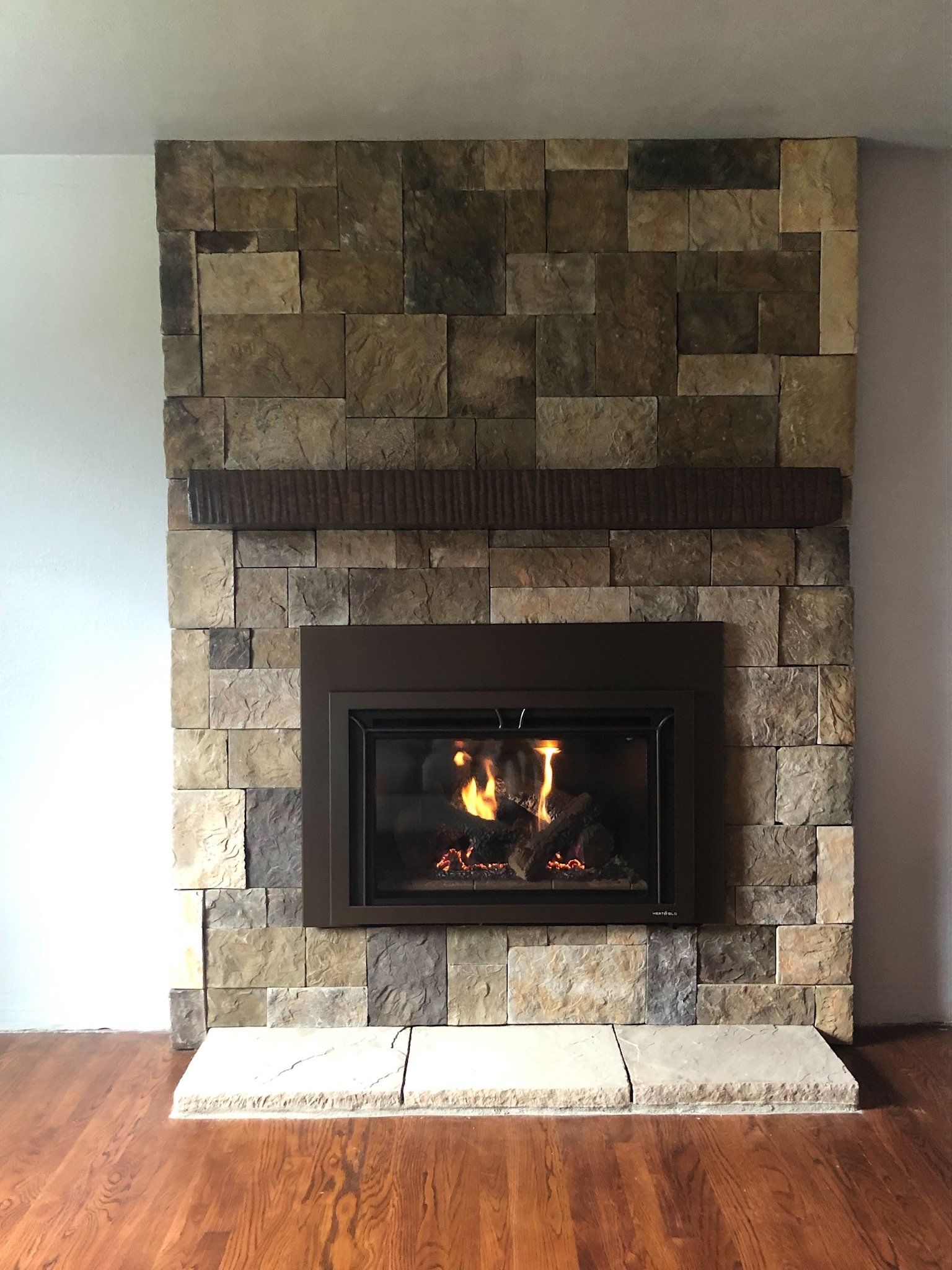A fireplace with a stone wall and a wooden floor