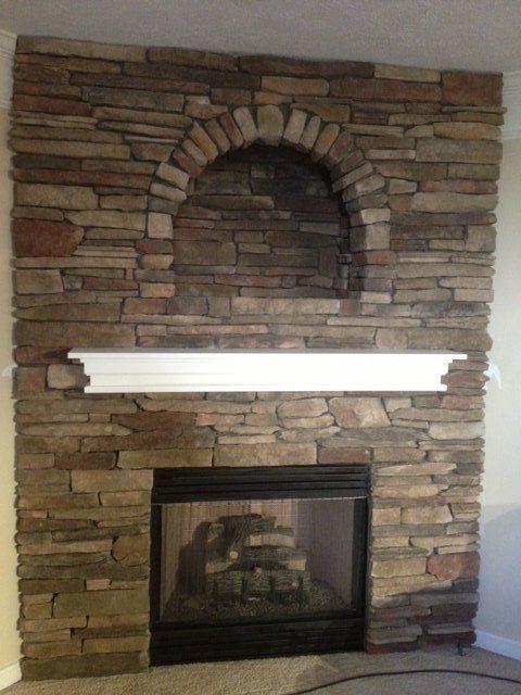 A stone fireplace with a white mantle in a living room