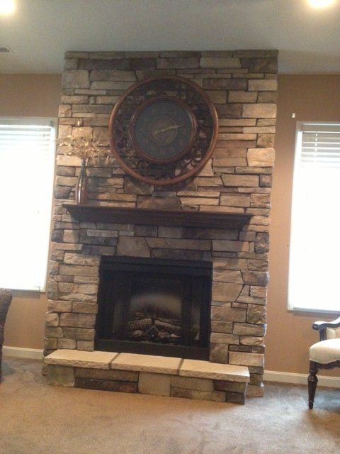 A stone fireplace with a clock above it