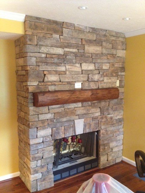 A stone fireplace with a wooden mantle in a living room