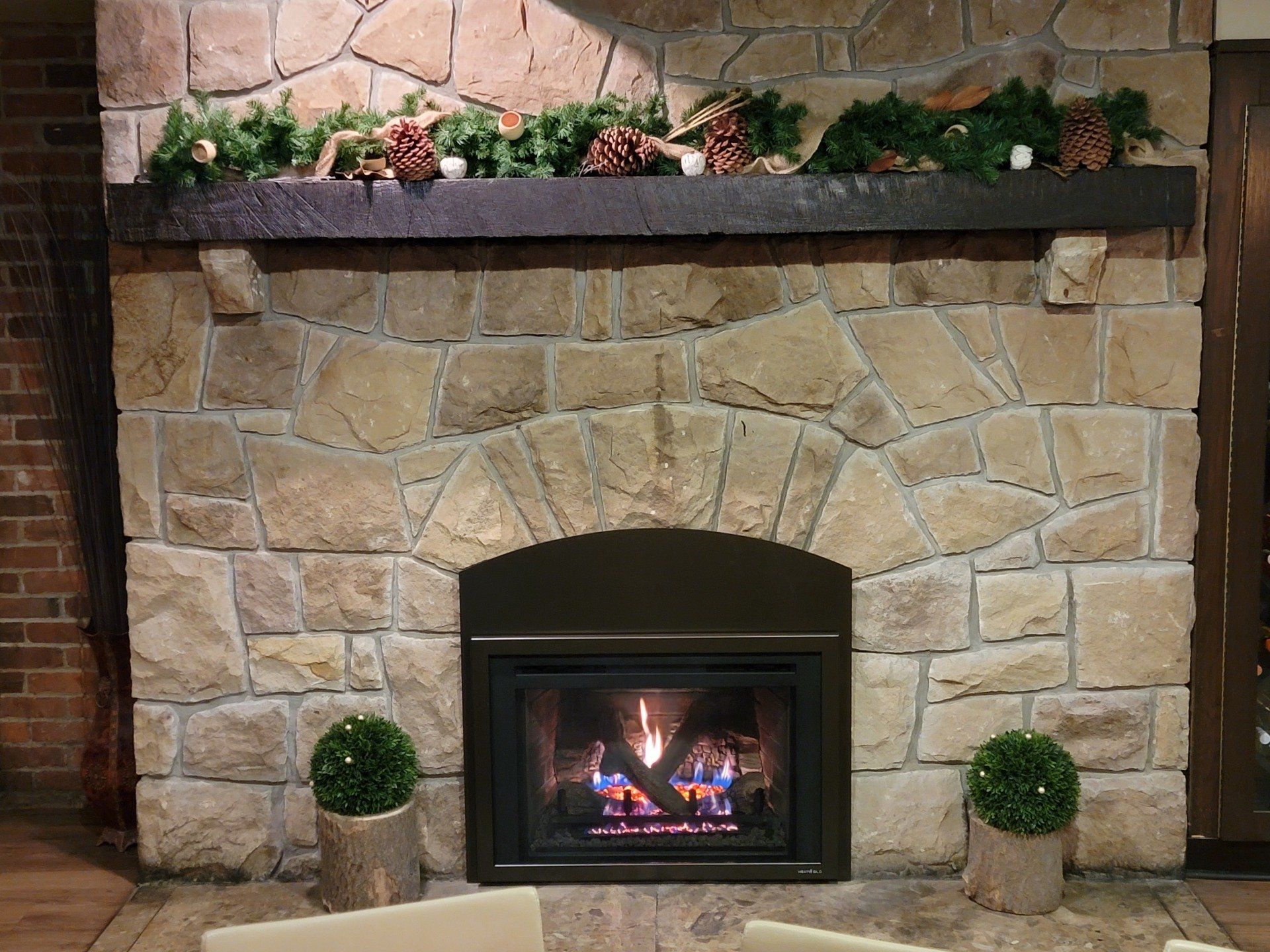 A large stone fireplace with a mantle decorated for christmas