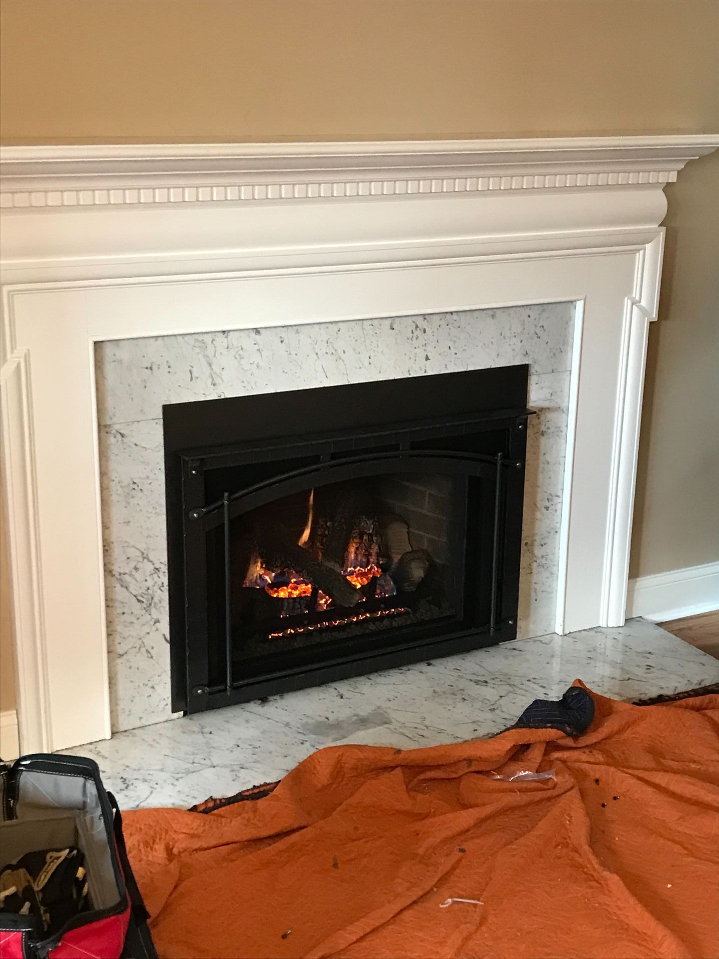 A fireplace with a blanket on the floor in front of it.