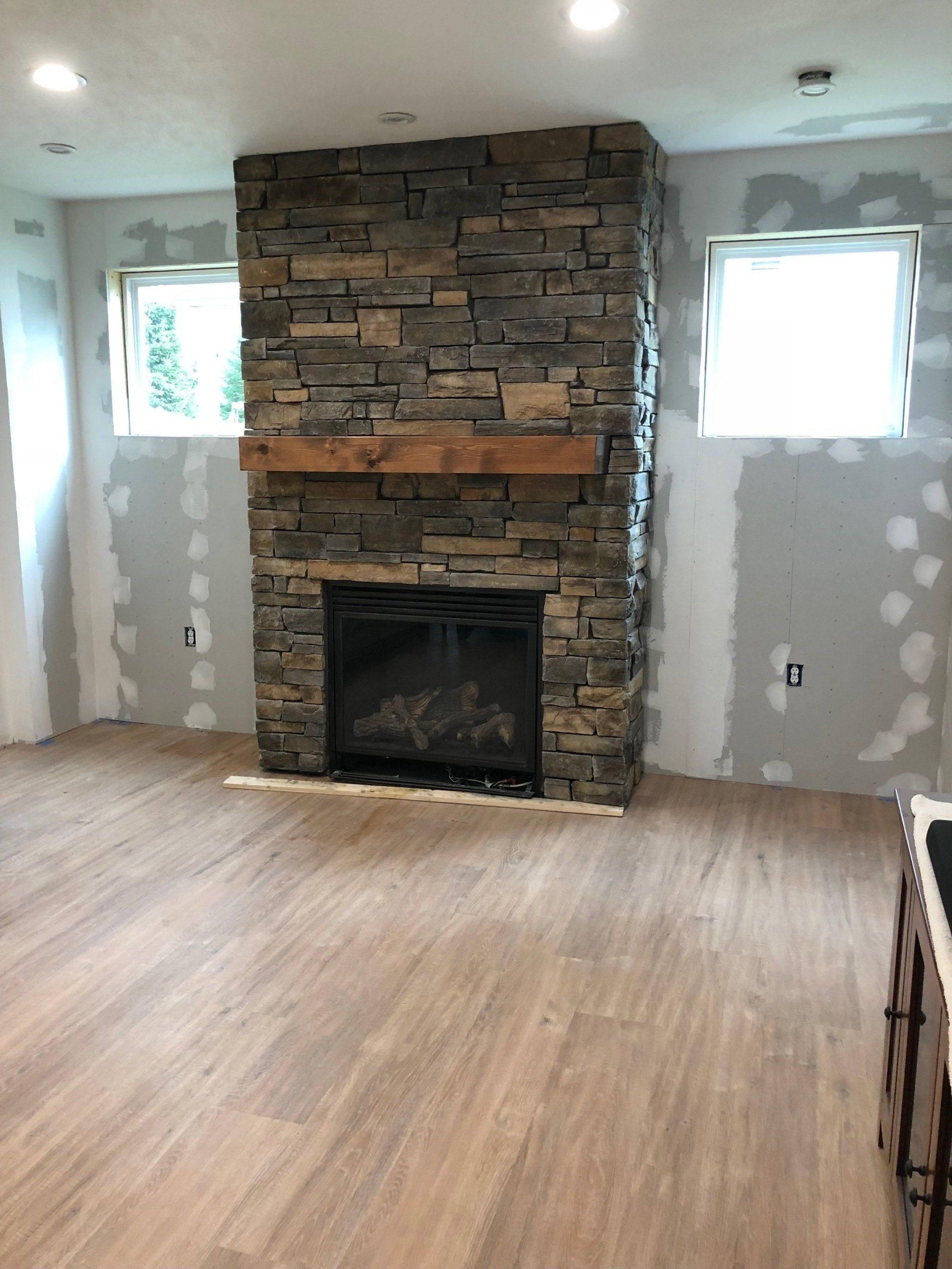 A living room with a stone fireplace and a wooden floor.