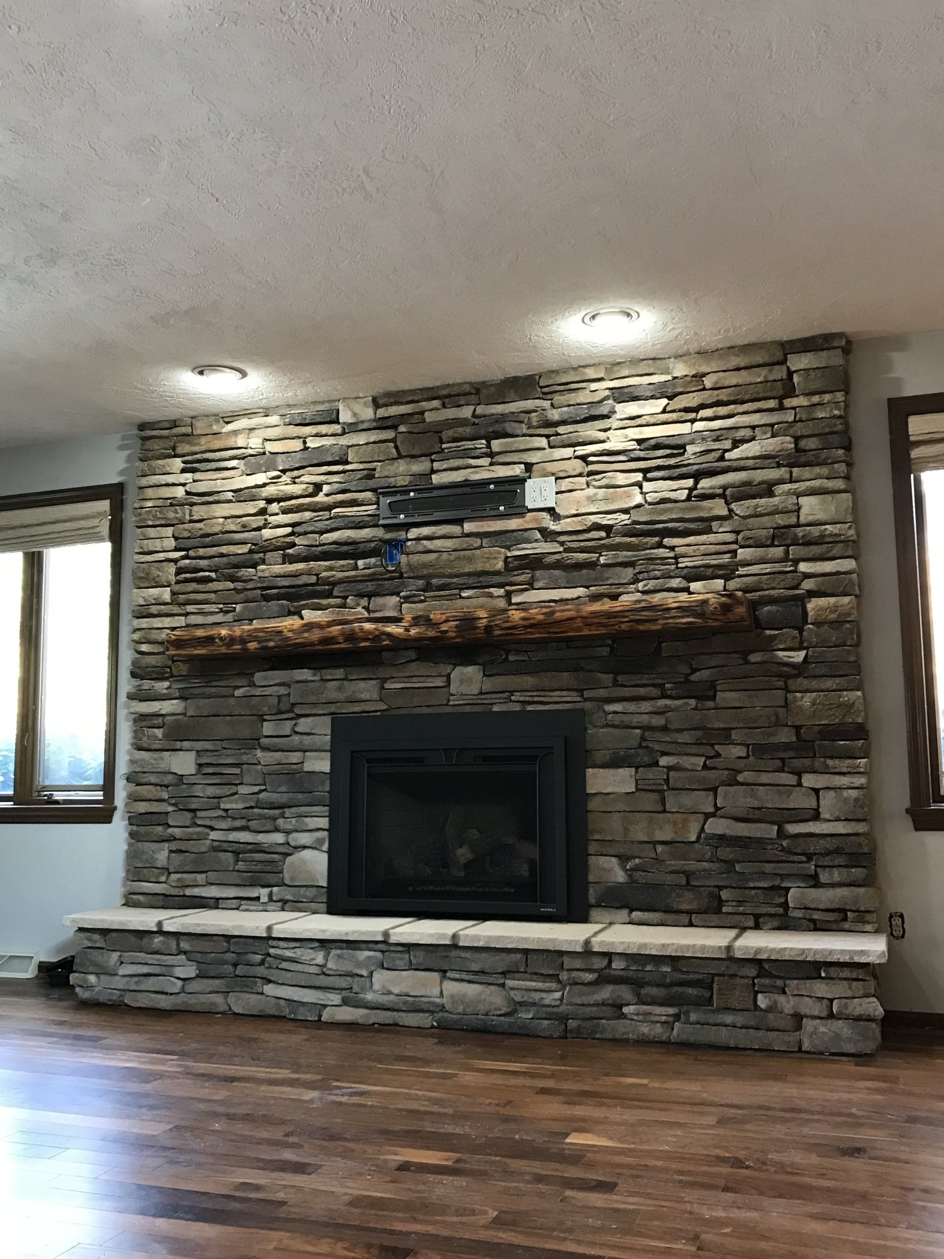 A living room with a large stone fireplace and a wooden floor