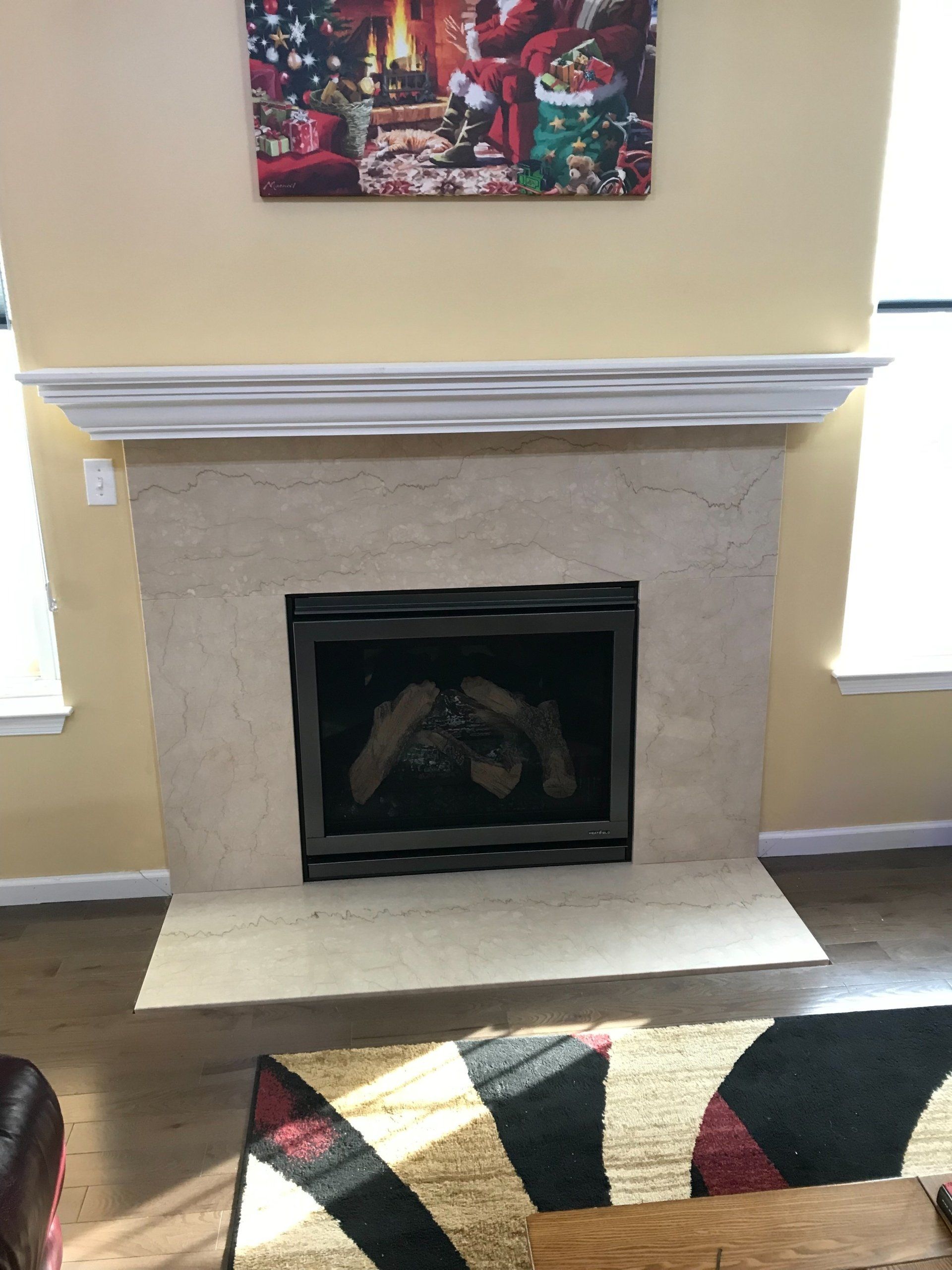 A living room with a fireplace and a painting on the wall above it.