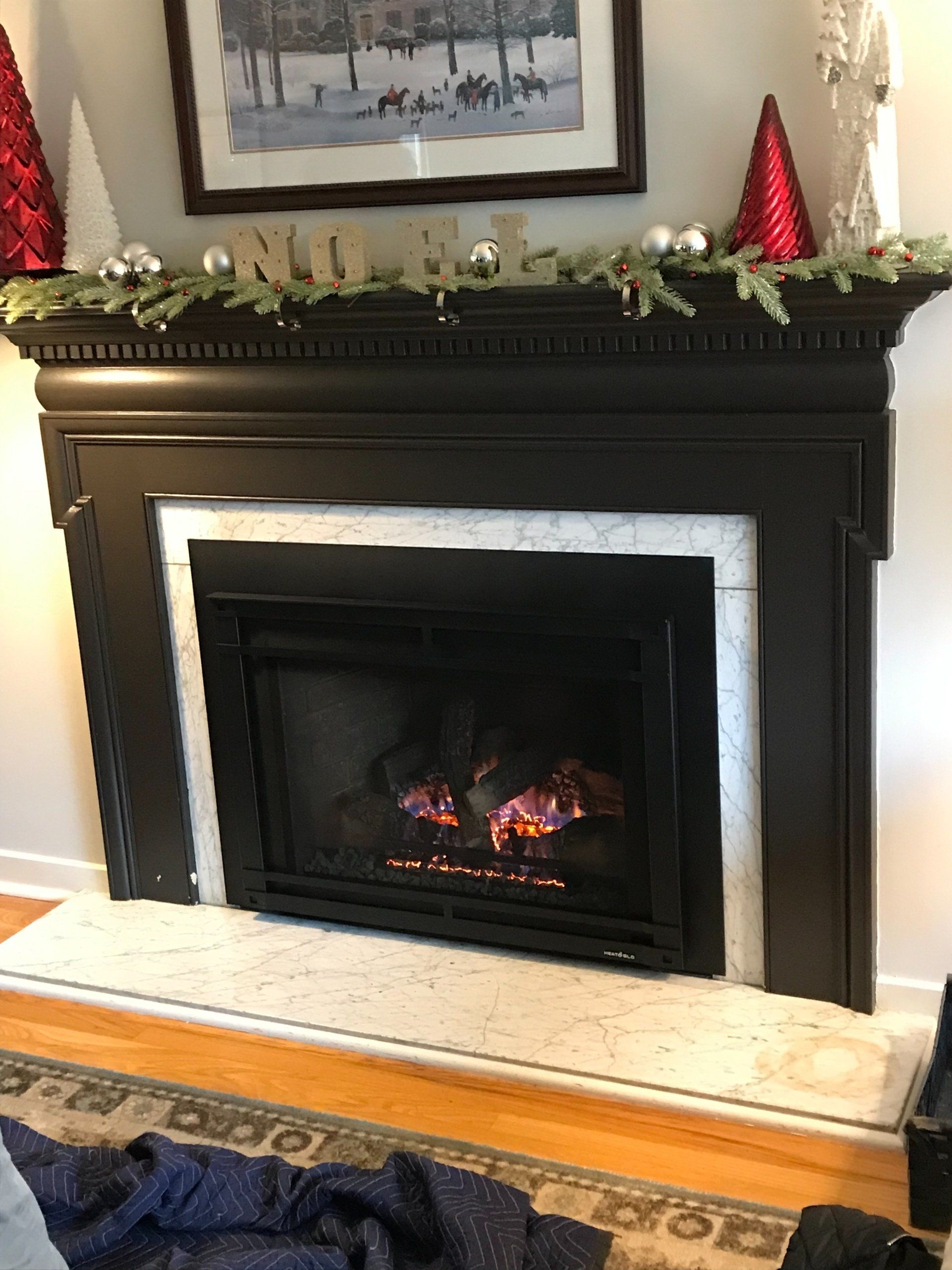 A living room with a fireplace and a mantle decorated for christmas.