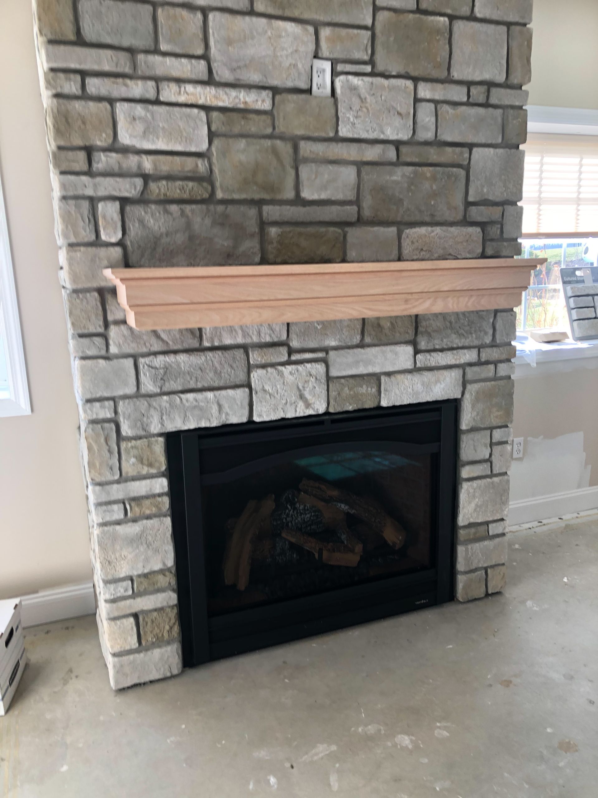 A stone fireplace with a wooden mantle in a living room.