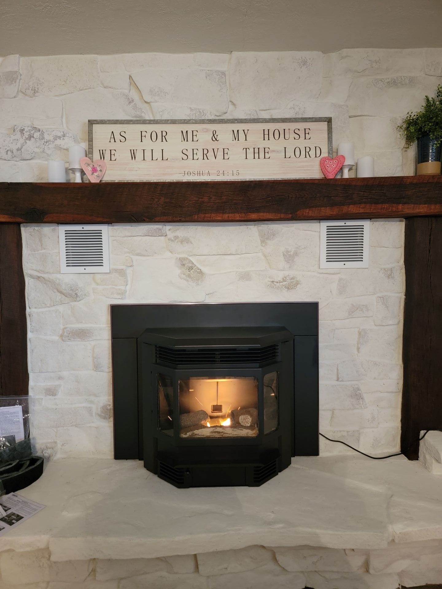 A fireplace with a wood stove in it and a sign on the mantle.