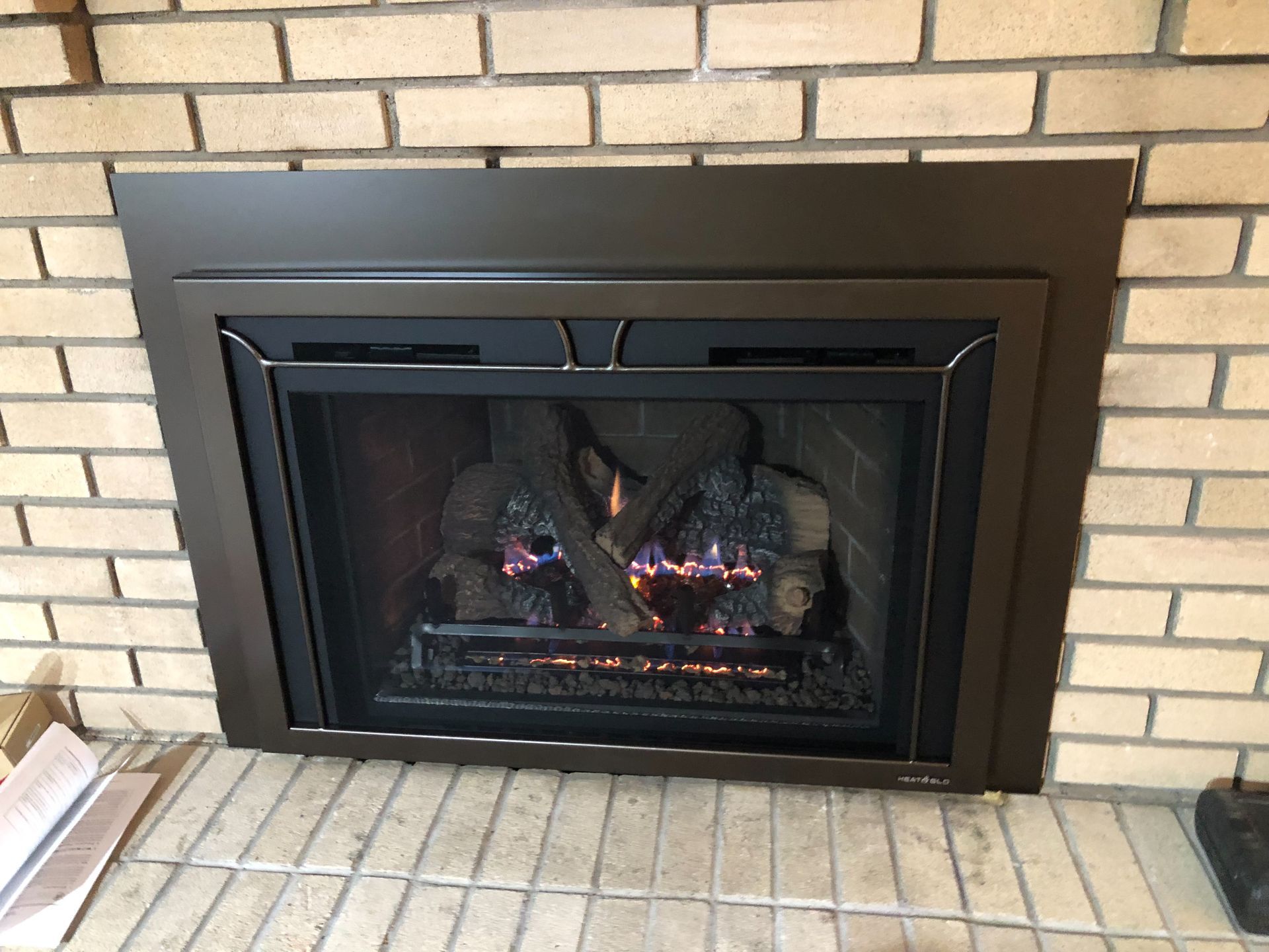 A gas fireplace is built into a brick wall in a living room.