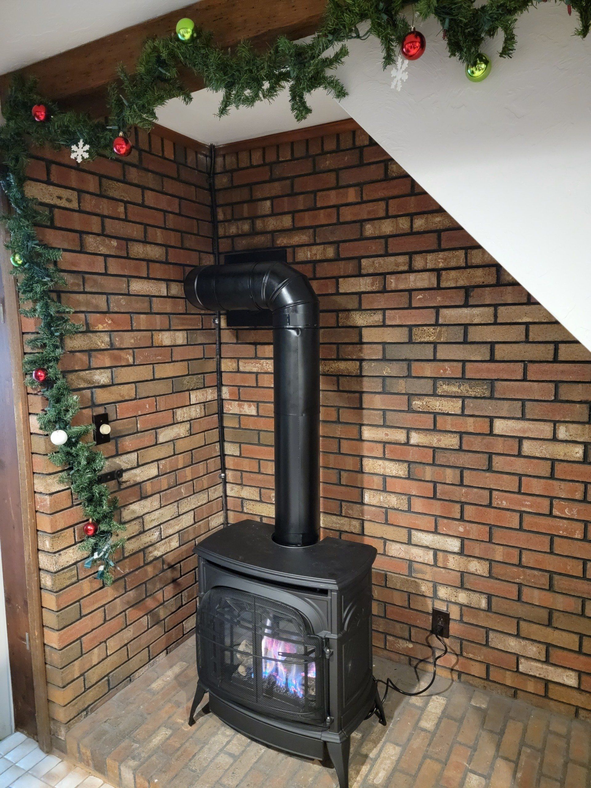 A black wood stove is sitting in front of a brick wall.
