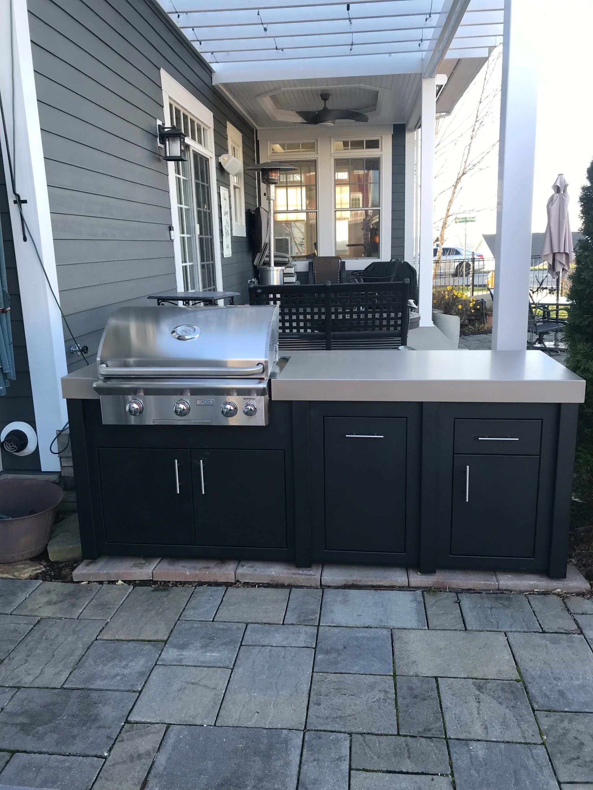 A grill is sitting on a patio next to a house.