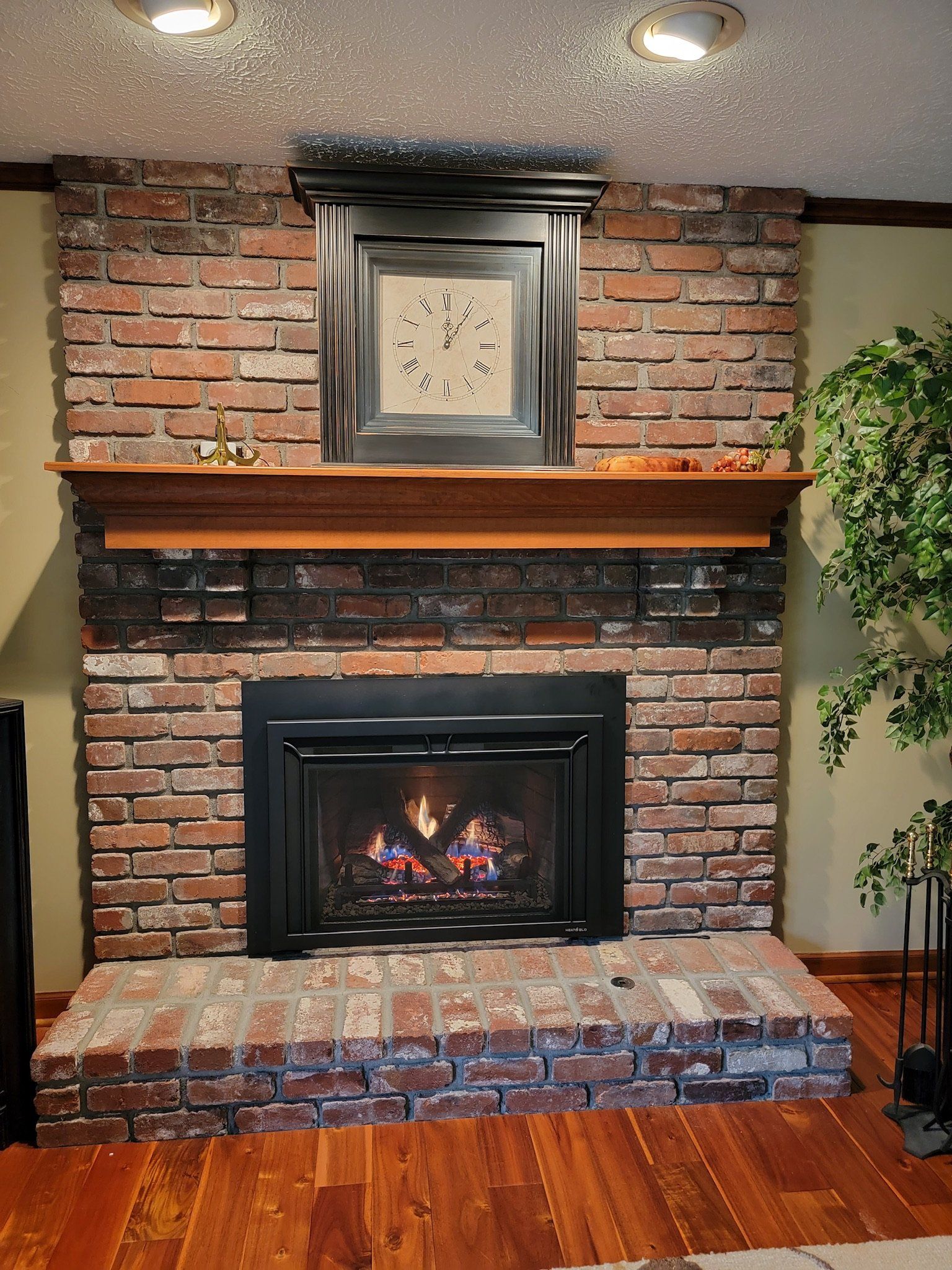 A living room with a brick fireplace and a clock above it