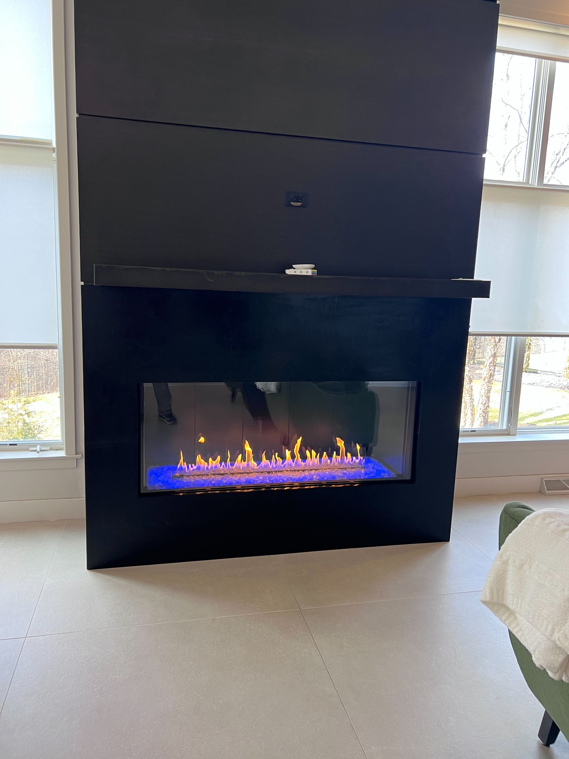 A fireplace is sitting in a living room next to a window.