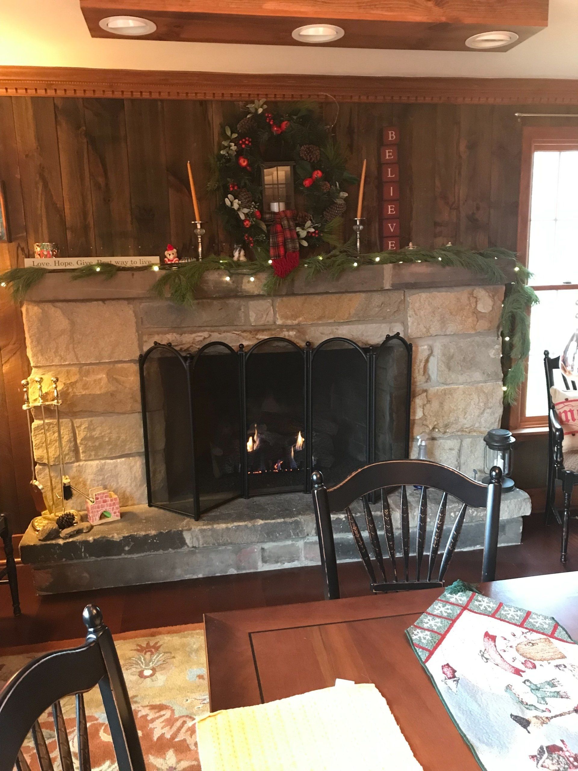 A living room with a fireplace and a christmas tree on the mantle