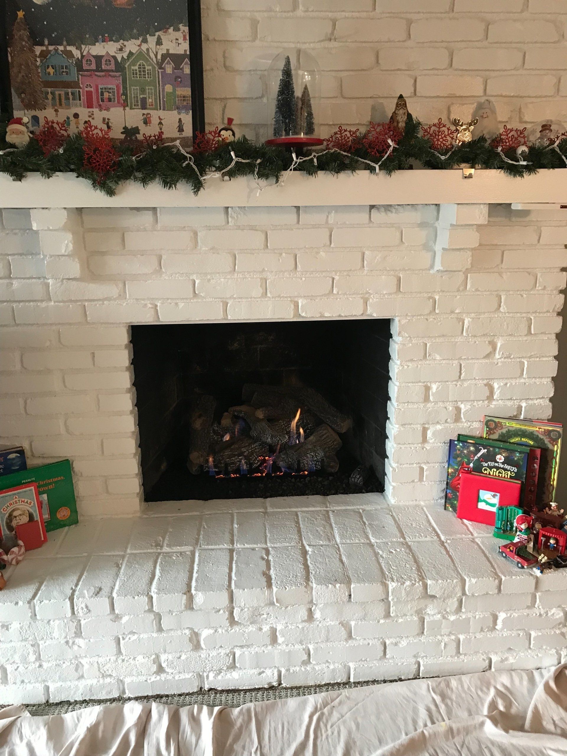 A white brick fireplace with a mantle decorated for christmas.