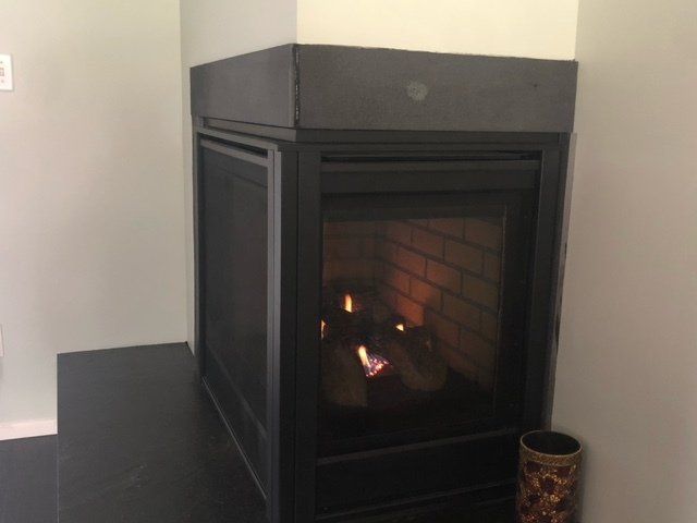 A fireplace is sitting in a corner of a room next to a vase.