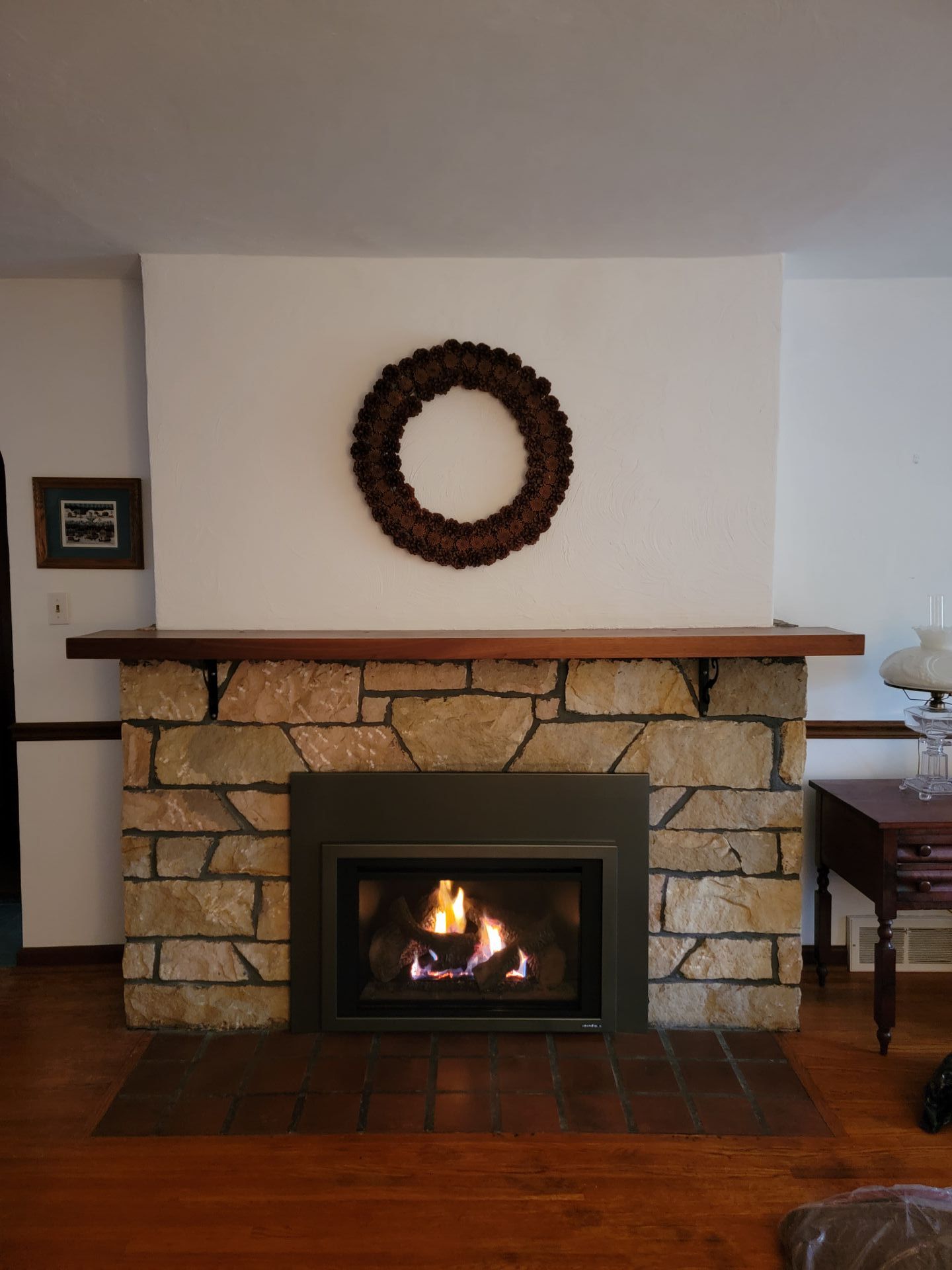 A fireplace with a wreath on the wall above it