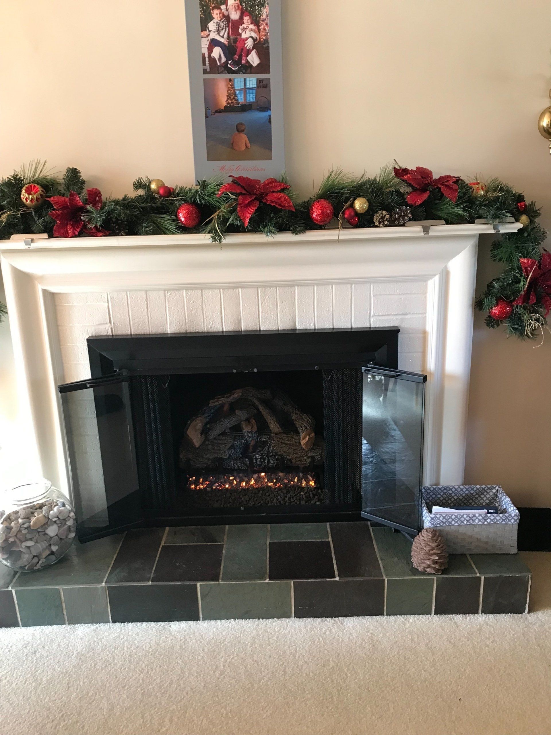 A fireplace in a living room decorated for christmas with a picture on the mantle.