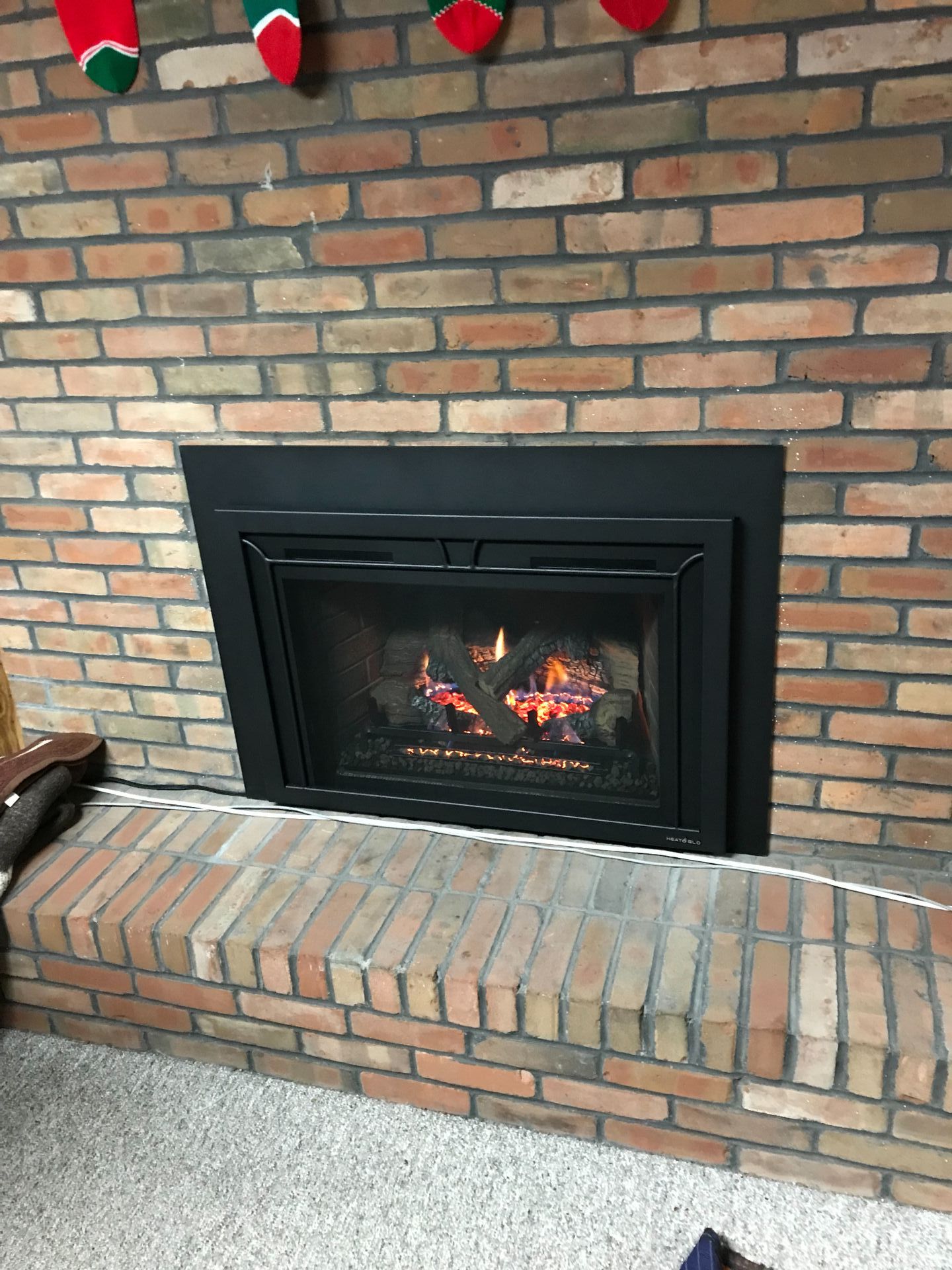 A fireplace in a living room with stockings hanging on the wall.