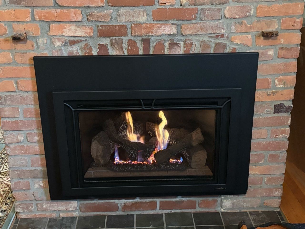 A gas fireplace is built into a brick wall in a living room.