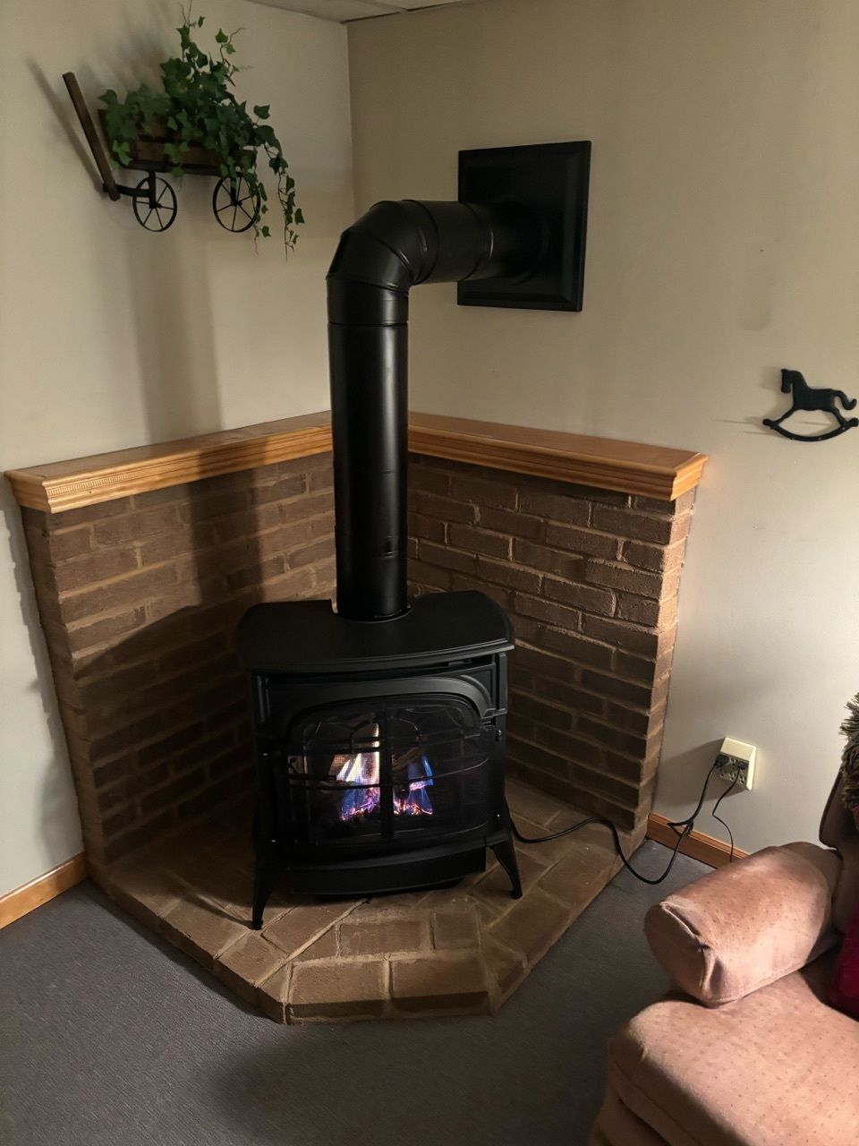 A wood stove is sitting in the corner of a living room next to a brick fireplace.