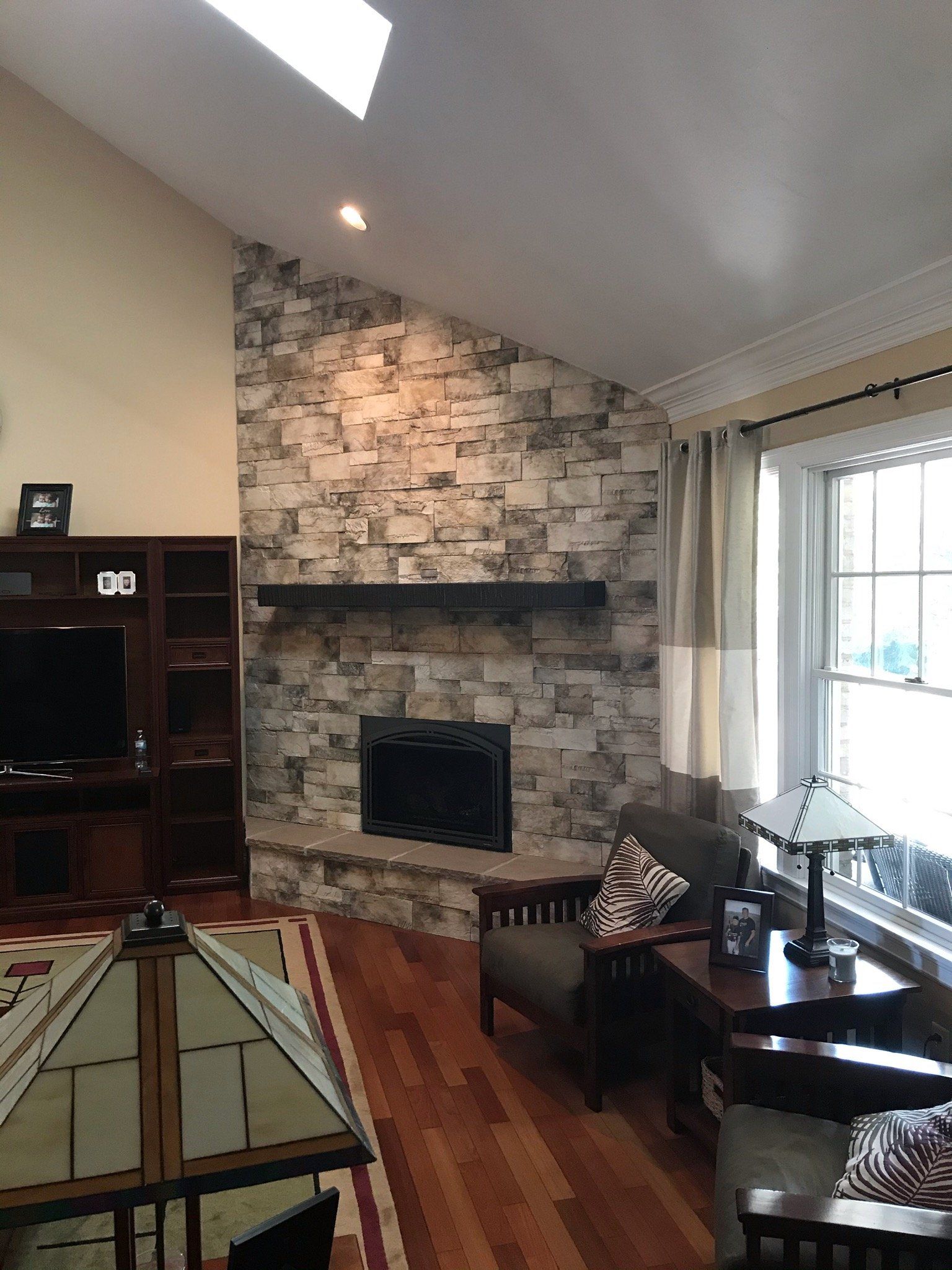A living room with a stone fireplace and a flat screen tv