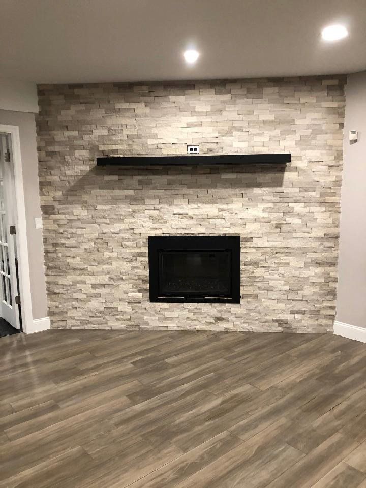 A living room with a fireplace and a shelf on the wall.