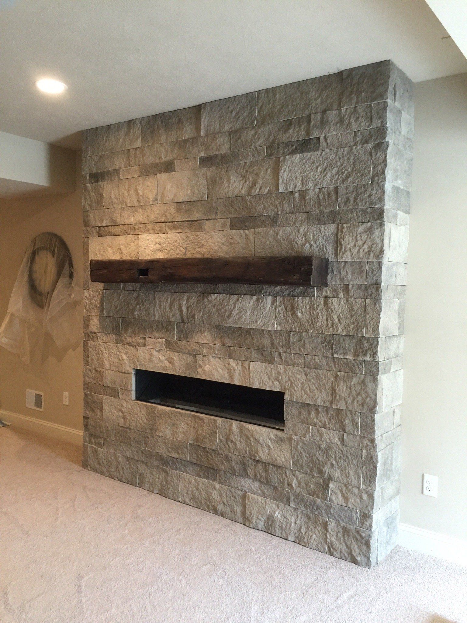 A stone fireplace with a wooden mantle in a living room.