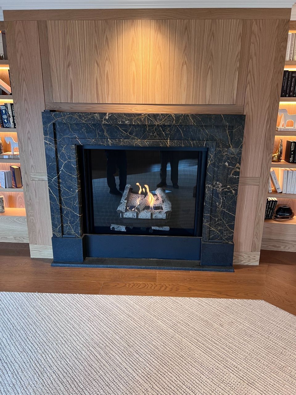 A fireplace is sitting in a living room next to a bookshelf.