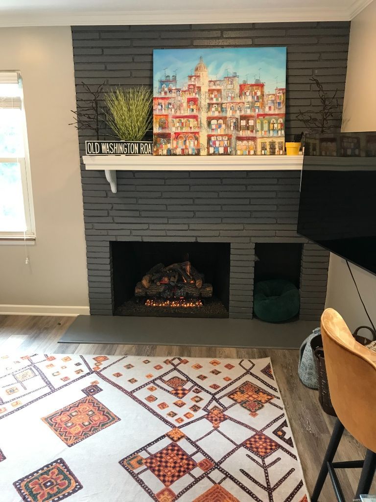 A living room with a fireplace and a painting on the mantle.