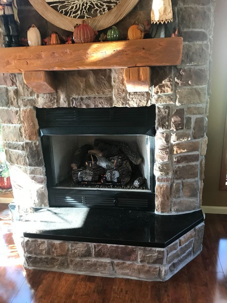 A stone fireplace with a wooden mantle in a living room.